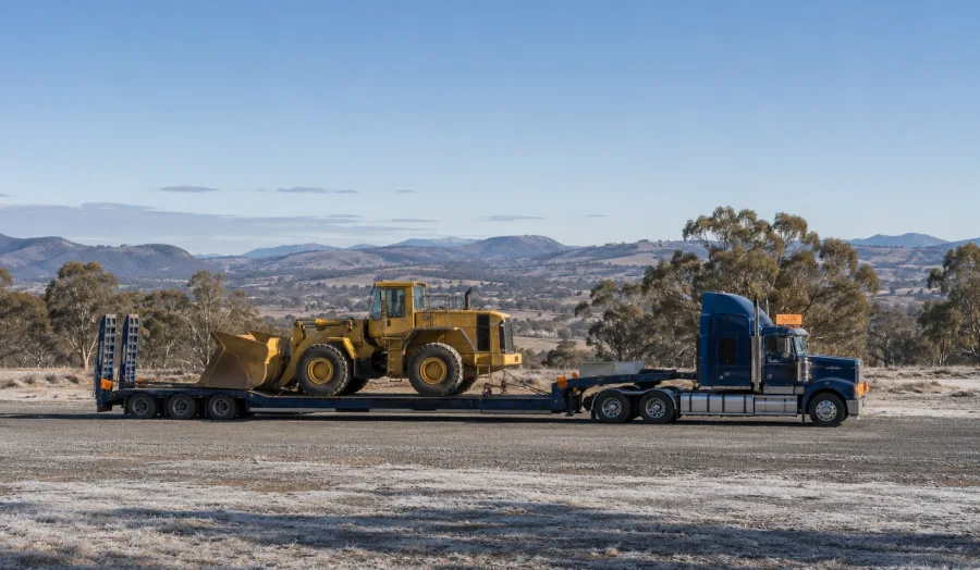 Low-loader with an earthmoving machine parked in tablelands country