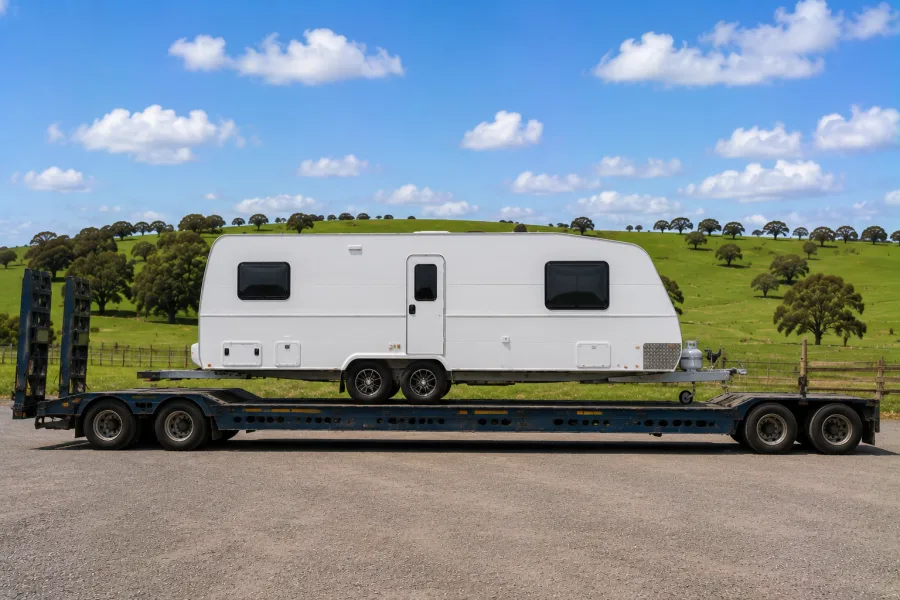 Touring caravan on a drop-deck against green south-east farmland