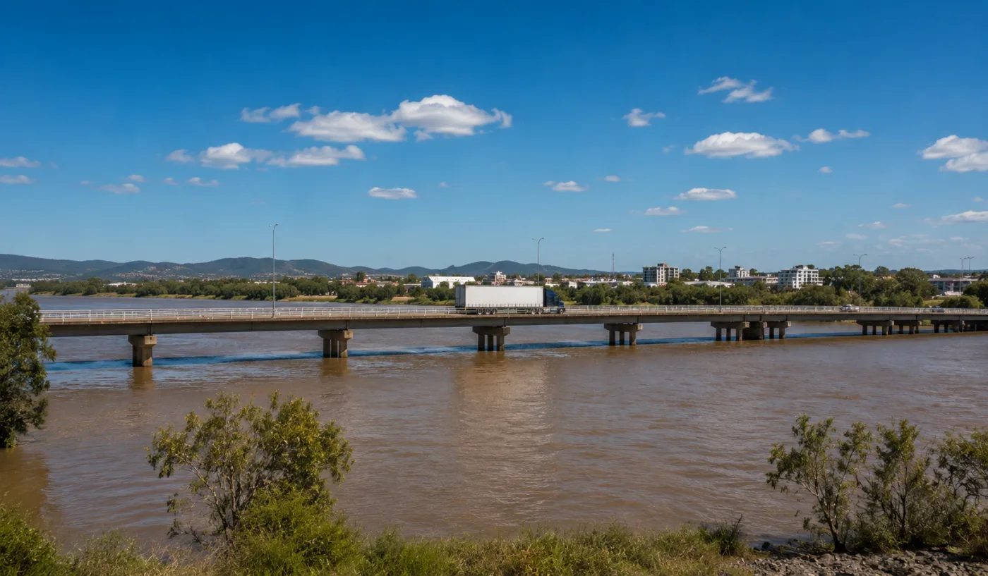 Semi-trailer crossing a long bridge over the wide brown Fitzroy River
