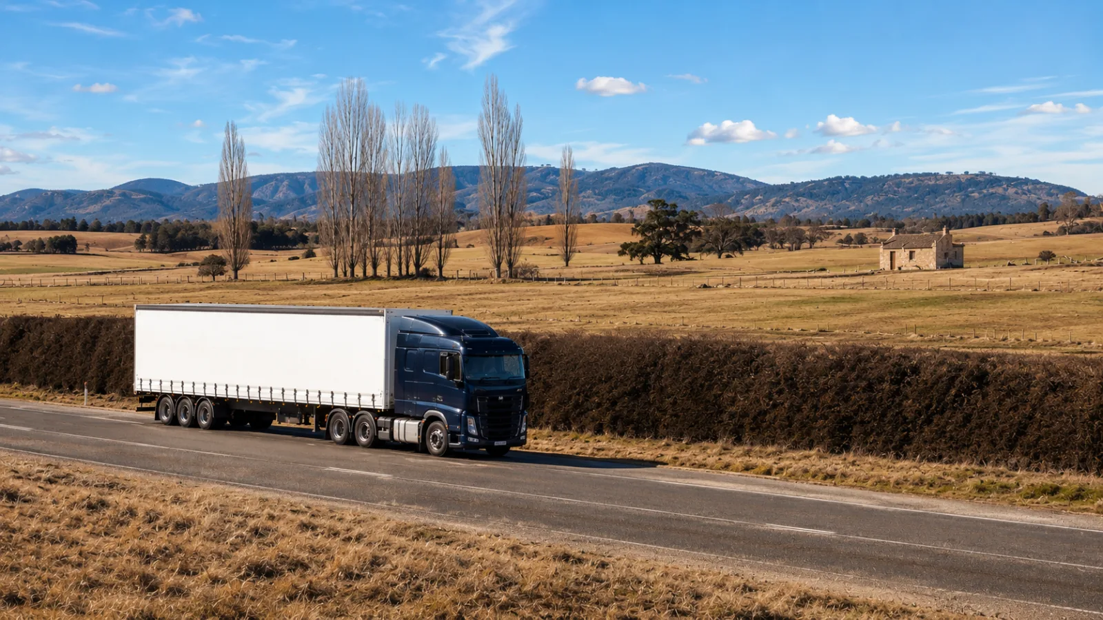 Semi-trailer on the Midland Highway through Tasmanian midlands grazing country