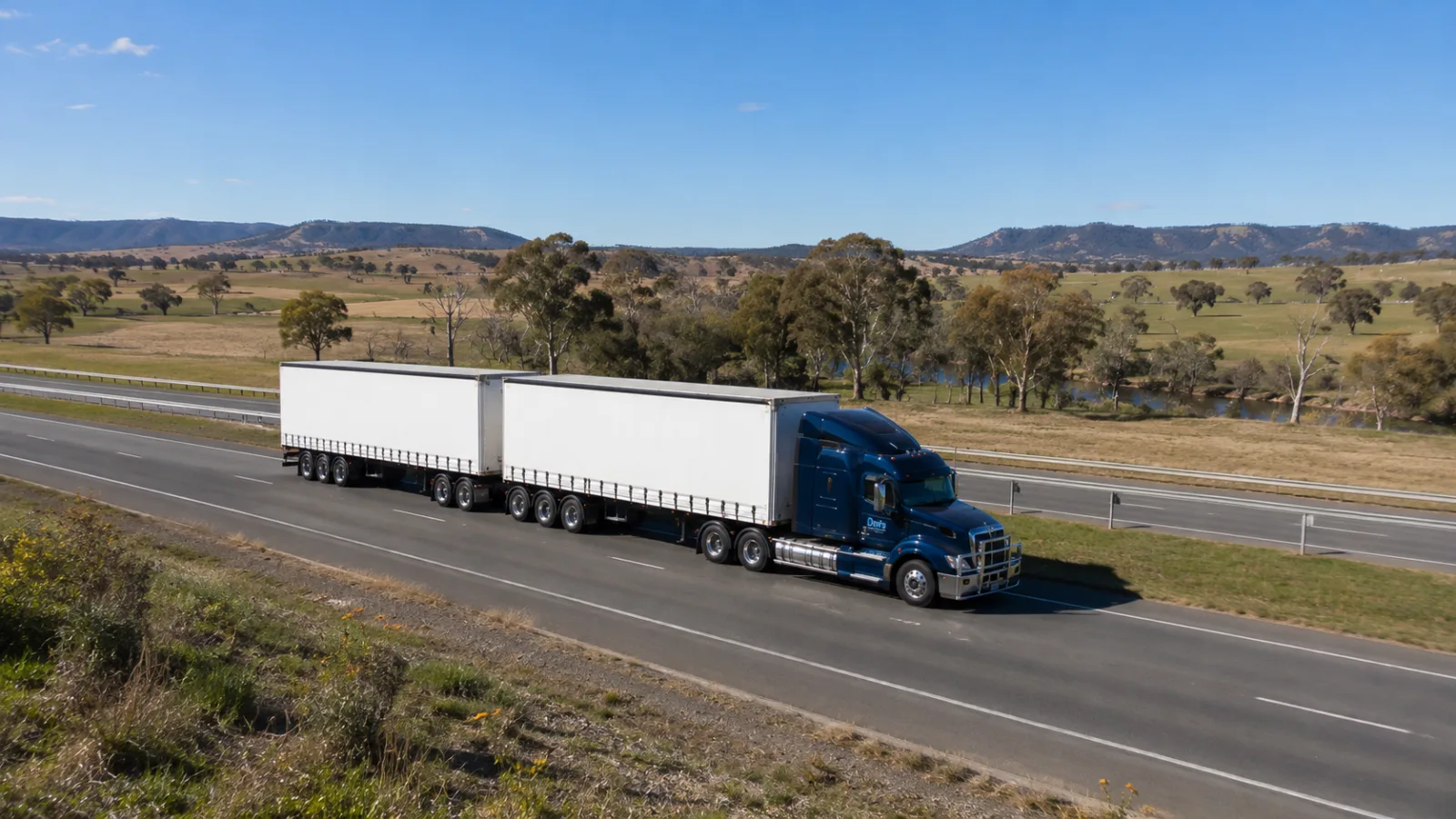 B-double on the dual carriageway Hume Highway through green tablelands country