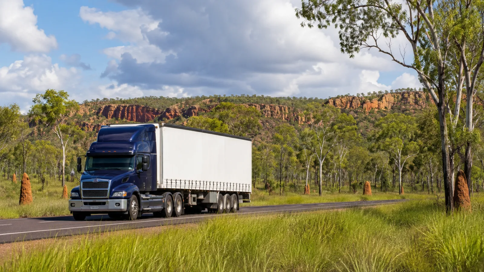 Semi-trailer on the Stuart Highway through Top End savannah with escarpment behind