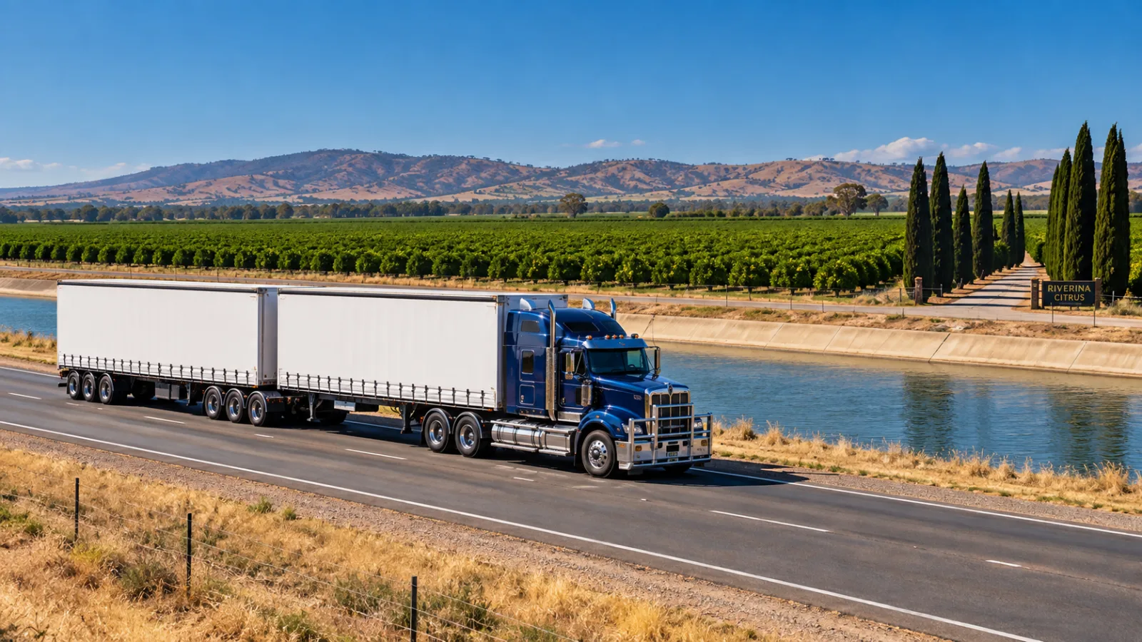 B-double on a road beside an irrigation channel and citrus orchards near Griffith